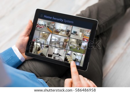 Man looking at home security cameras on tablet computer Royalty-Free Stock Photo #586486958