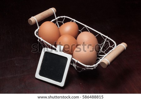 eggs in mini basket and mini blackboard with dark wood background. Isolated conceptual image