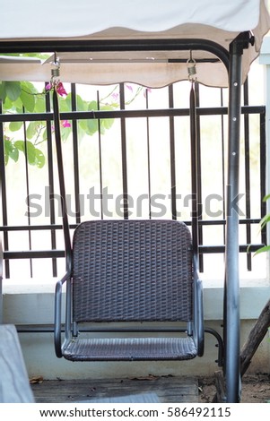 Wicker chair in the garden.Outdoor Rattan Grey Lounge Dining Chair Or Armchair Made from Eco-Friendly Poly Wicker Material With Black Metal Armrest. Weather Resistant. 