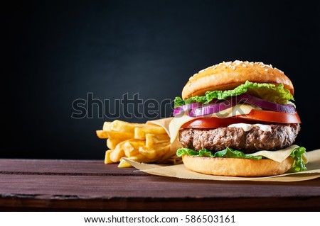 Craft beef burger and french fries on wooden table isolated on black  background. Royalty-Free Stock Photo #586503161