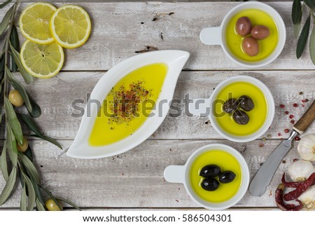 Different colors of olives in white bowl, olive oil mixed with pomegranate molasses and spices in a round shaped porcelain plate. Aerial view. Copy space available.