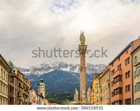 Perspective view along Maria-Theresien-Strasse with St. Annas column and Alps with snow caps on the background, Innsbruck, Austria.