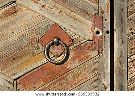 Wooden old fence with an iron grip. Metal circle on a rustic door. Retro and vintage