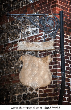 Shield shape wooden old vintage sign hanging, brick wall background 
