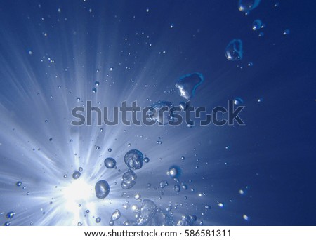Underwater photo of the sun with rays and water bubbles 