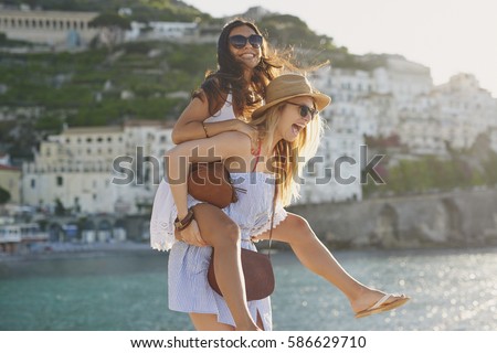 Piggyback happy tourist friends having fun on summer travel adventure vacation laughing Royalty-Free Stock Photo #586629710