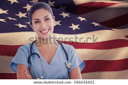 Smiling female doctor looking at camera against waving flag of america