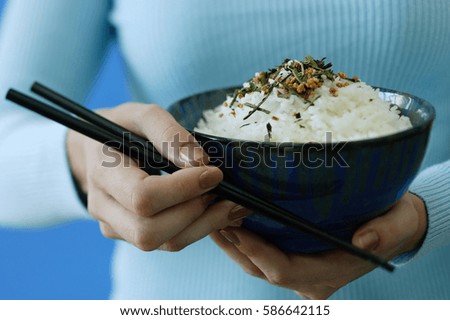 Woman holding bowl of rice and chopsticks