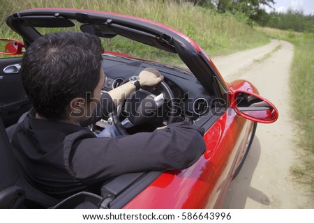 Man driving red convertible sports car