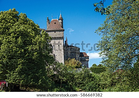 Partial view of Castle of Menthon-Saint-Bernard with trees and blue sky, near the Lake of Annecy. Department of Haute-Savoie, Auvergne-Rhone-Alpes region, south-eastern France.