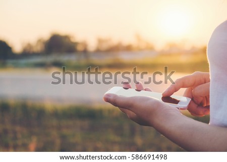  bright day of a young woman holding and using smartphone