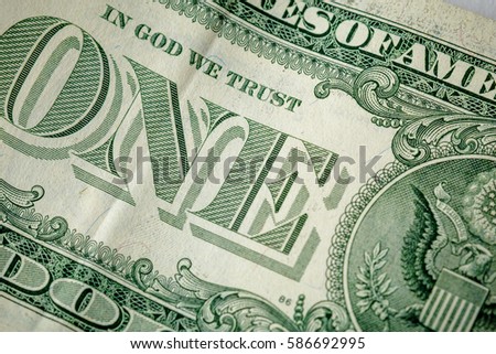 Caption: "one" and "in God we trust" on the one dollar bill. Cash, money, close-up photo