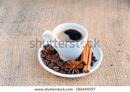 A hot Cup of coffee on a saucer on the background of burlap.