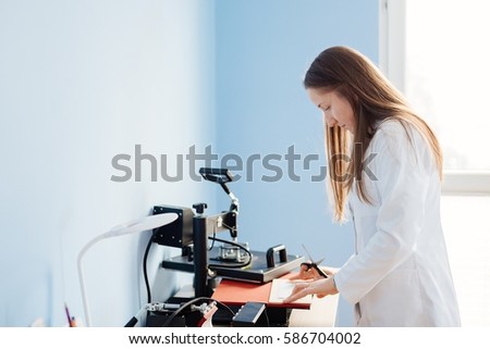 Young woman in white lab thermal transferring image to wooden plank