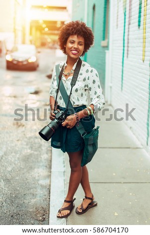Pretty girl taking pictures in city with sunset background
