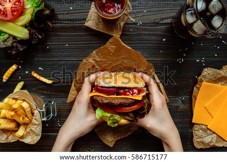 Fresh tasty burgers with french fries, sauce and drink on the wooden table top view.