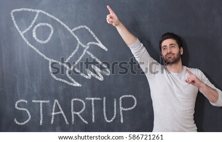 Startup business concept. Portrait of man on chalkboard background