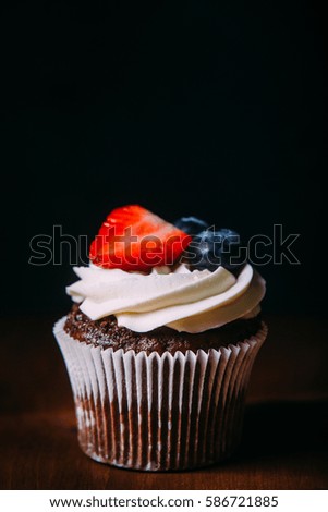 Fresh tasty chocolate cupcakes with berries. Selective focus. Dark wooden background.Rustic style, place for text.