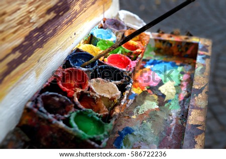 Artist at work. The workplace of the artist, brushes, paints and canvas. Multicolor oil paints on a palette close up.