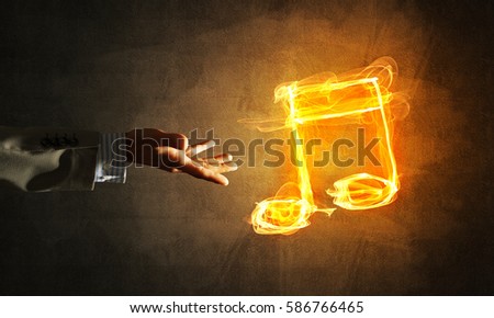 Close up of person hand and fire music symbol on dark background
