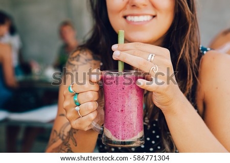 Young girl having a good morning healthy breakfast smoothie drink made of super foods, fruits, nuts, berries Royalty-Free Stock Photo #586771304