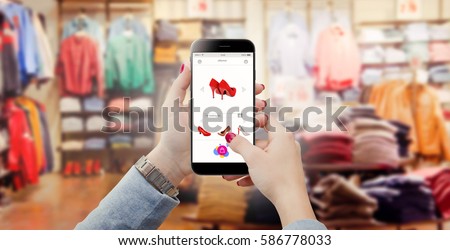 Woman in clothing store holding phone in hands and searching online shoes 