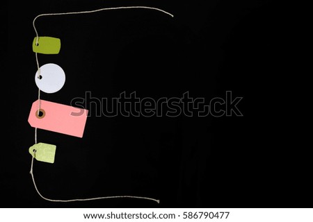 Blank paper tags on a string against black background. Copy space in right part of horizontal photo. High angle view.