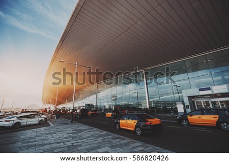 Cabstand in front of entrance of modern airport in Barcelona, cabrank with a lot of taxis near glass facade of contemporary Airport terminal in Spain with road, huge ceiling and parking lot