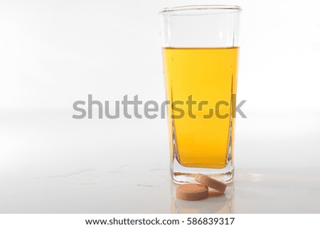 A dissolving tablet in an orange drinking water over white background