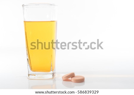 A soluble tablets or pills and a glass of water over white background