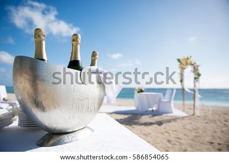 Beautiful close-up picture of icy champagne container on the beach. Chilled ice bucket with Bright background, shining sun and sea, in Mauritius tropical island