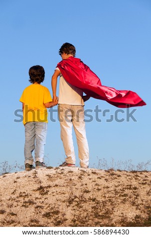 Two boys playing superheroes on the sky background