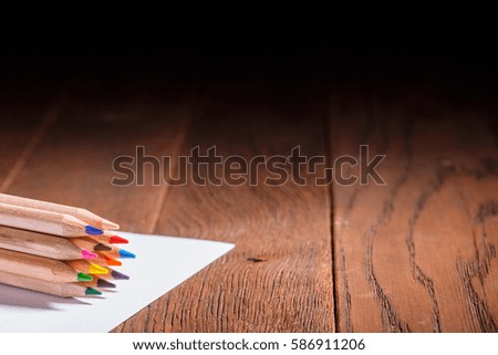 Multicolored pensils on the white paper on a wooden table. Back to school. Copy space.