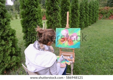 Lovely artist paints butterfly painting in park