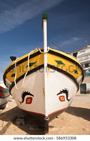 close up on beautiful colorful wooden traditional touristic boat on sandy beach in carvoeiro in blue sky, algarve, portugal