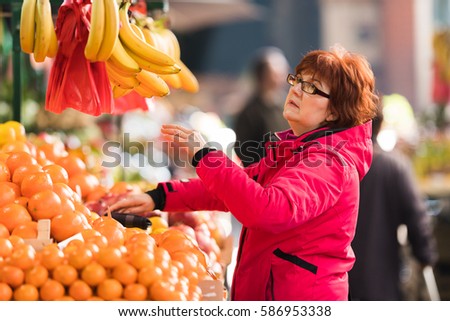 Middle age woman buying fruits at market place 
