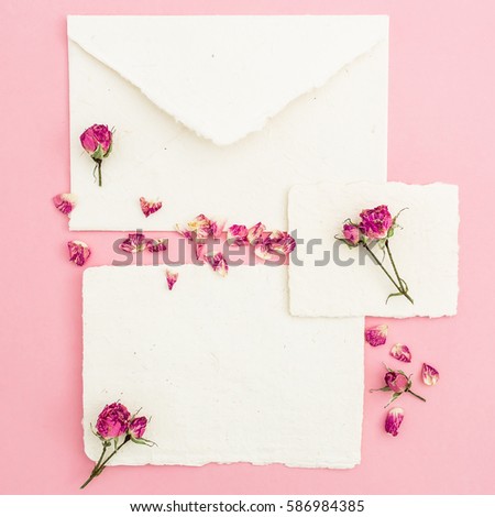 Paper envelope and cards with roses flowers on pink background. Flat lay, top view. Retro background