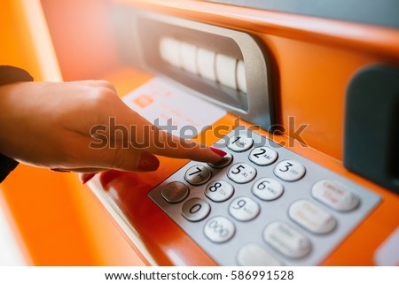 Woman entering pin code on the ATM keypad