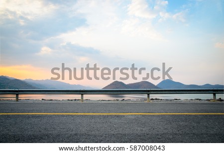 A photo of the road near the dam with sunset scene Royalty-Free Stock Photo #587008043