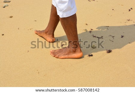 African american man walks on a sand beach. Close up of male feet and golden sand. Beach walk. Summer activity. Beautiful holiday background