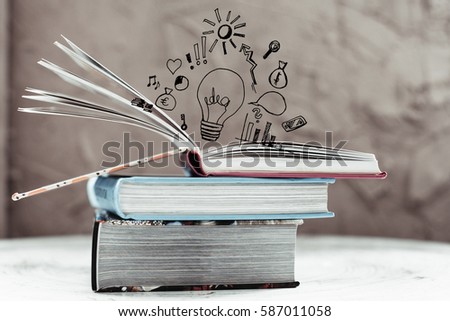 Opened book with business sketches and painted bulb as a concept idea over background