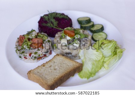 Risotto roll with vegetables together with a silver fork and knife on a white plate