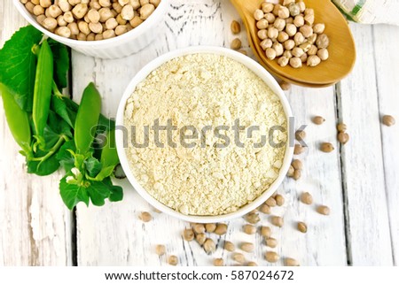 Flour chickpeas and chick-pea in white bowls and spoons, pods of green beans, a doily on the background of wooden boards on top Royalty-Free Stock Photo #587024672