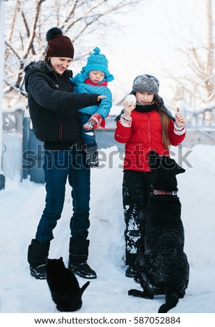 family plays with labrador in the snow