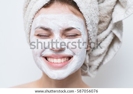 beautiful woman after shower with a towel on her head smiling cream on face. Royalty-Free Stock Photo #587056076
