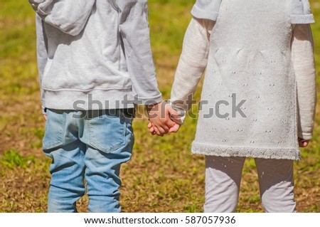 Two little kids holding hands. Small boy and girl shaking hands. Childhood friendship stock image. Child friends.