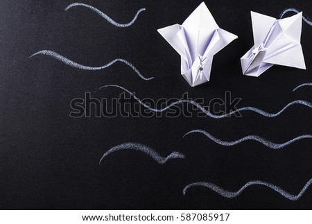 Pair of white swans, origami on a dark background. Top view, closeup