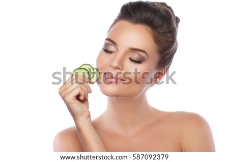 Young beautiful woman with cucumber slices  on white background