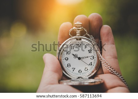 Hand holding retro stopwatch in natural background. Royalty-Free Stock Photo #587113694