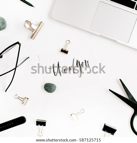 White office desk workspace with words thank you and supplies. Laptop, scissors, pen, clips, glasses and office supplies on white background. Flat lay, top view.